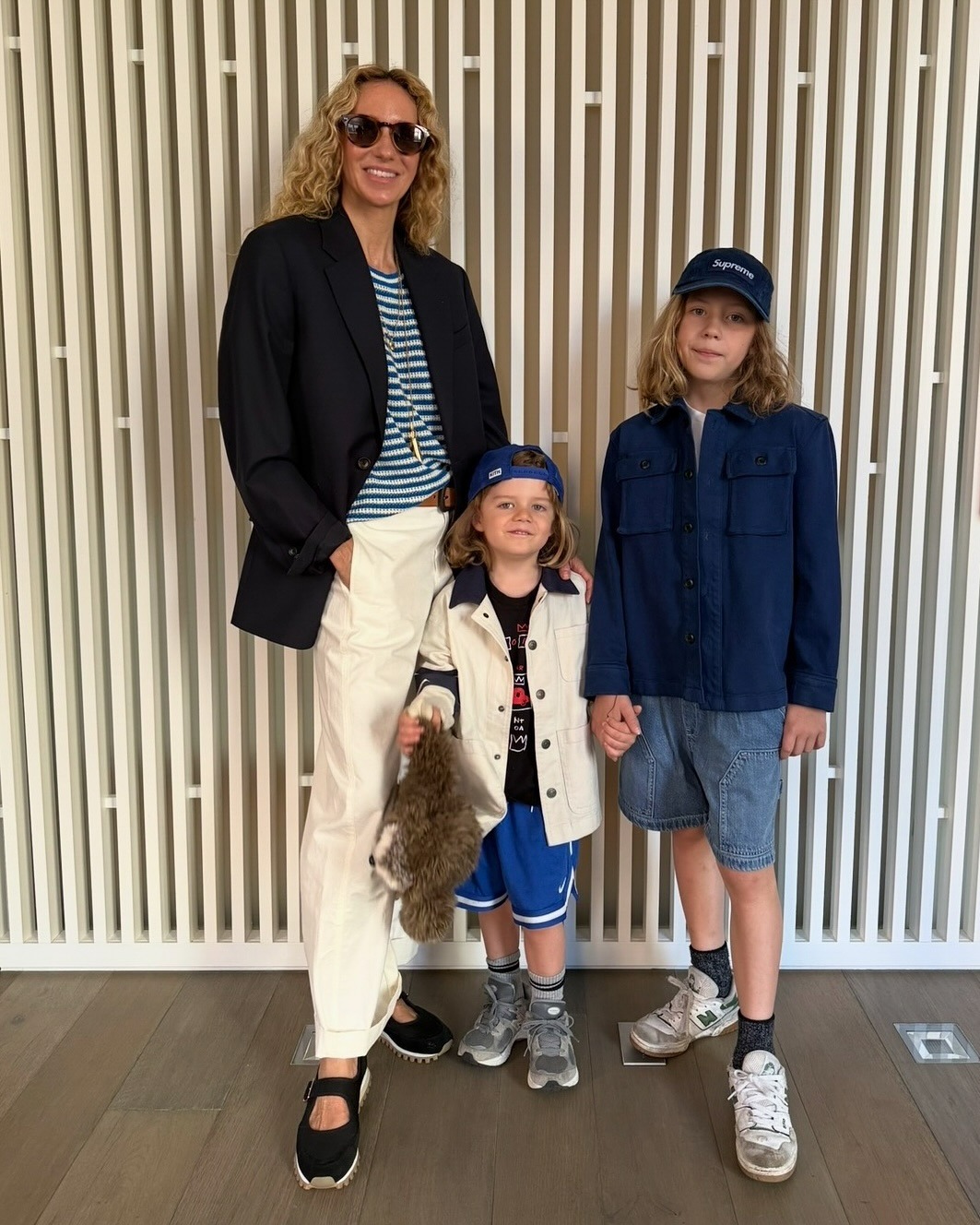 Olympia wears a stripe shirt, black blazer, white pants, and mary jane sneakers.