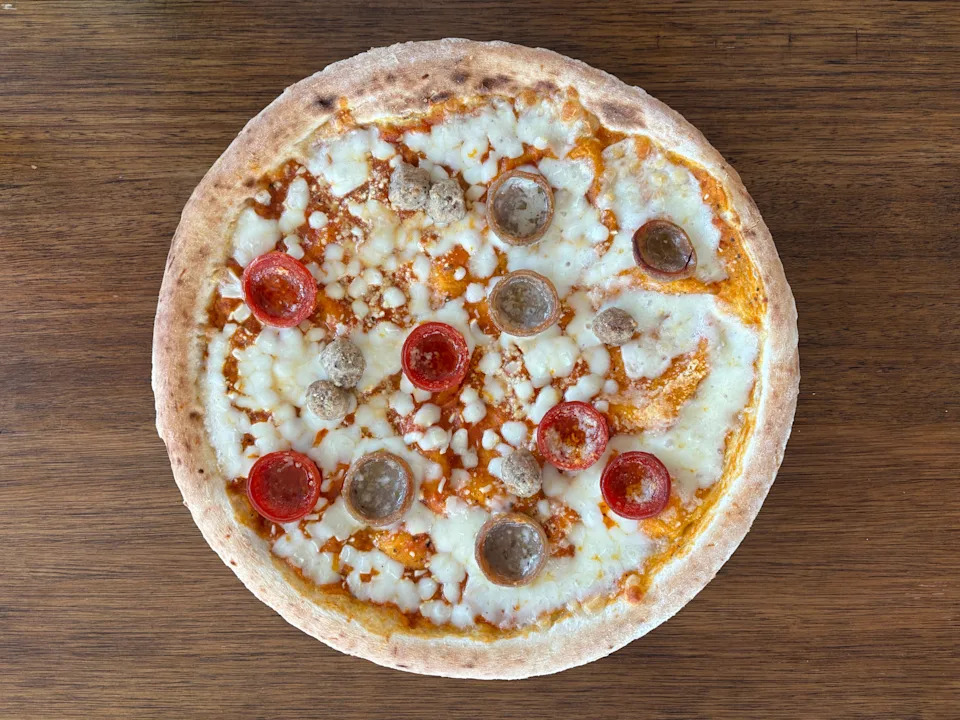 Pizza with cheese, pepperoni, and sausage on a wooden table
