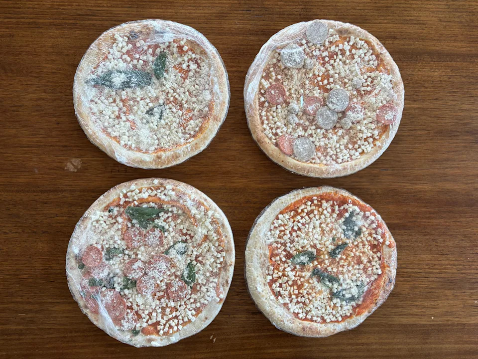 Four frozen mini pizzas with various toppings on a wooden surface