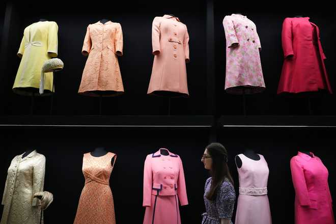 A member of Royal Collection Trust staff looks towards day wear worn by Princess Elizabeth, on display at 'Queen Elizabeth II: Her Life in Style' exhibition, to mark the centenary of the late queen's birth, at The King's Gallery at Buckingham Palace in London, Thursday, April 9, 2026. (AP Photo/Kirsty Wigglesworth)