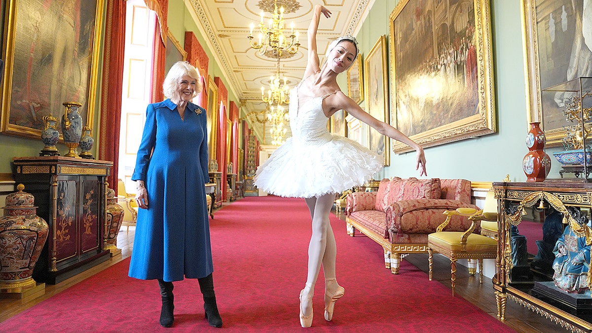 Queen Camilla standing next to ballerina Sangeun Lee performing at Buckingham Palace