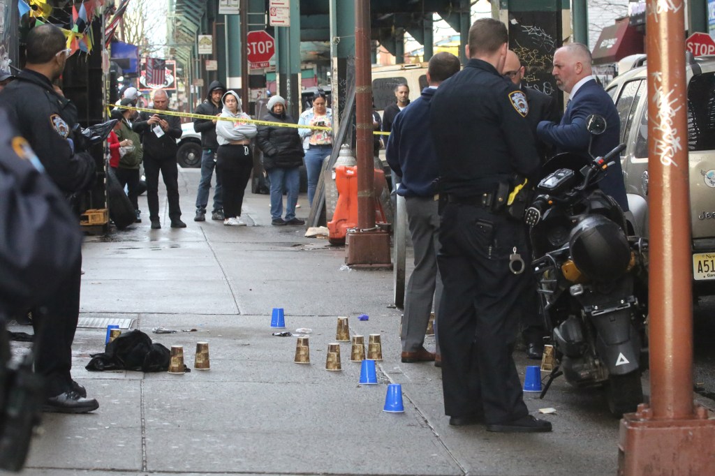 Police at a shooting crime scene in front of 2961 Fulton Street, with bullet casings marked by cups.