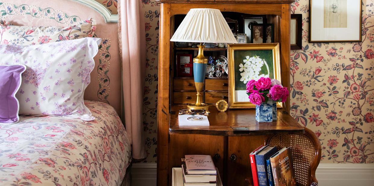 Cozy bedroom featuring floral wallpaper and an array of framed artworks.