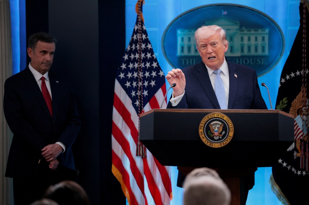 President Donald Trump speaks at a podium in the White House briefing room, accompanied by CIA Director John Ratcliffe.