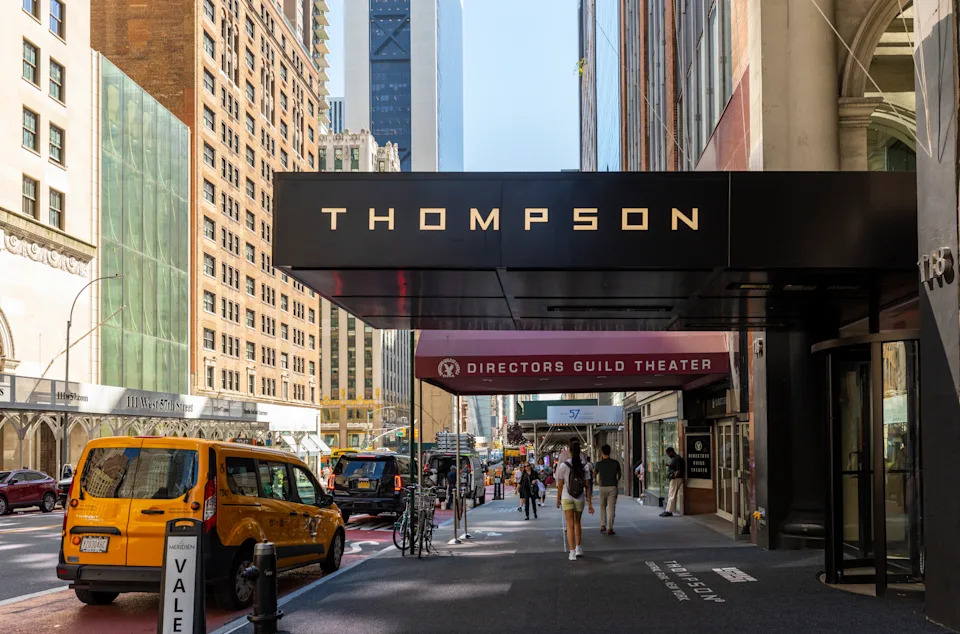 Thompson Central Park New York hotel exterior in Midtown Manhattan with street view of passing cars and pedestrians in New York City.