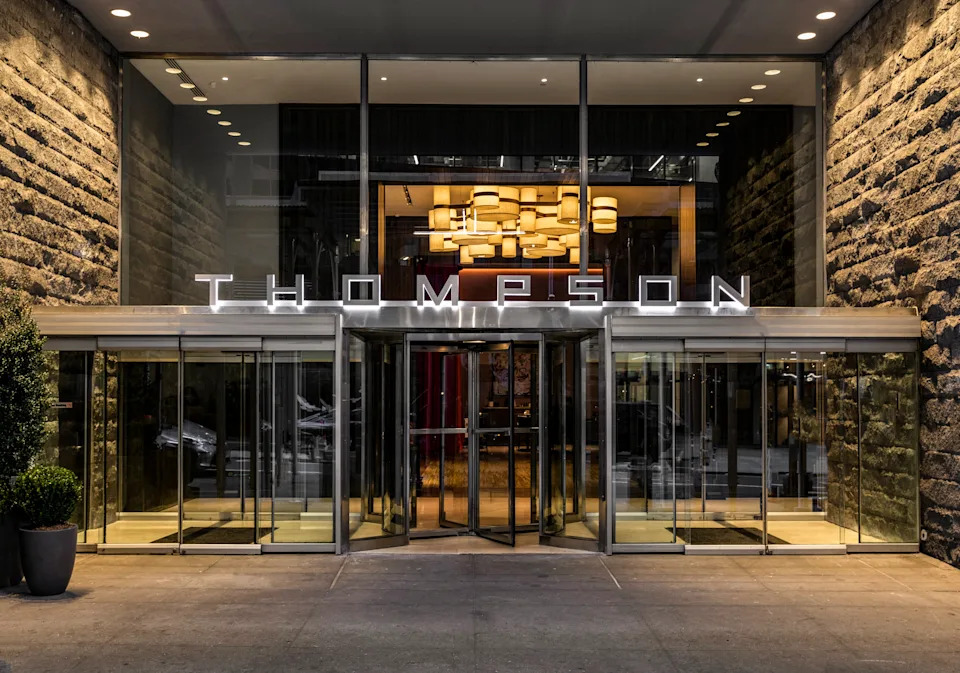 Entrance of Thompson Central Park New York in Midtown Manhattan, New York City, featuring modern glass doors and a welcoming hotel arrival area.