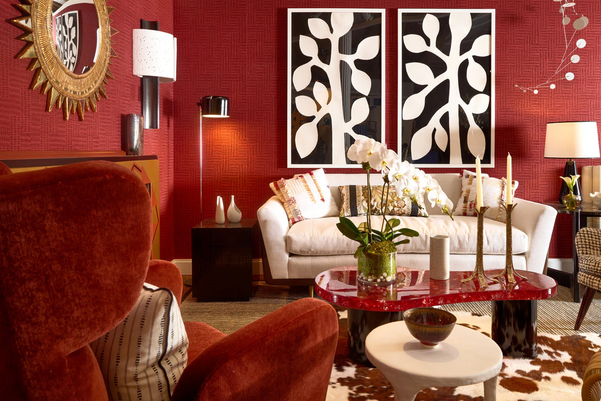 Modern living room with red walls, white sofa, abstract art, and stylish decor elements.