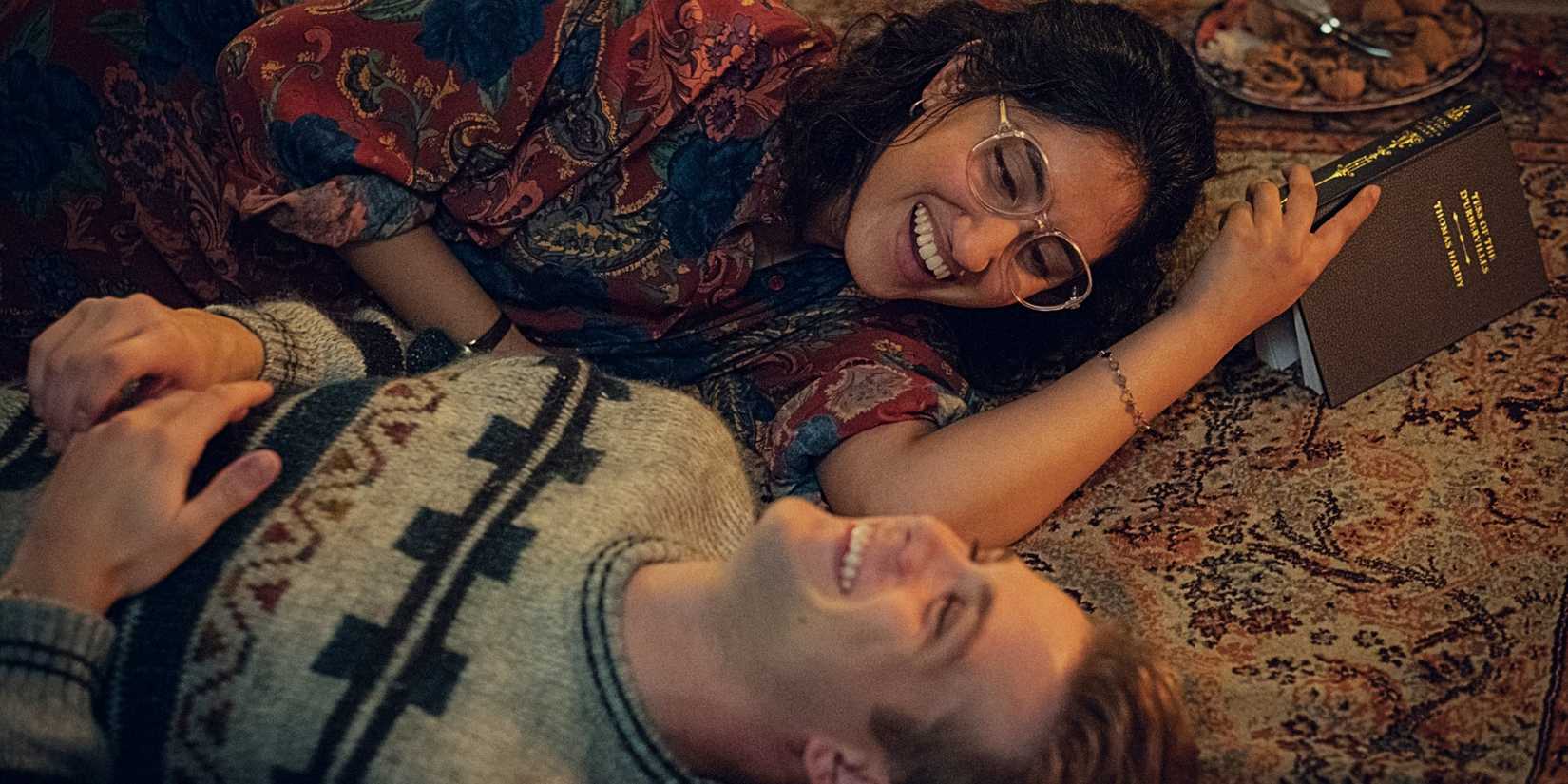 Emma and Dexter lying on the floor together and laughing in One Day.