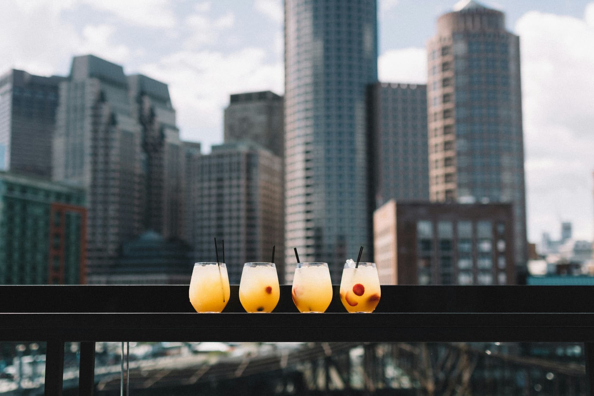 four drinking glasses on bar top with skyline in background