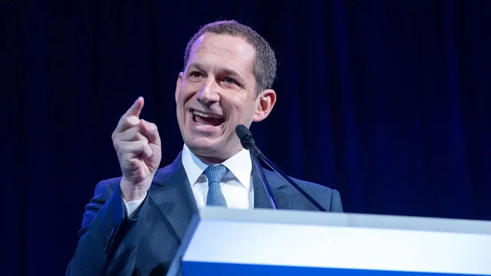San Francisco Mayor Daniel Lurie speaking at a podium and gesturing with his hand