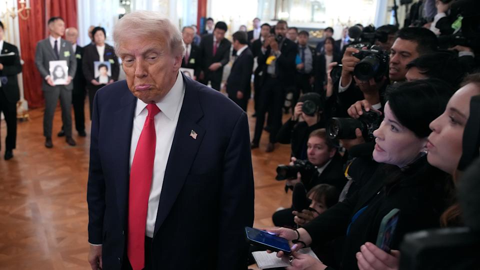 Donald Trump walks past reporters with a pouting expression.