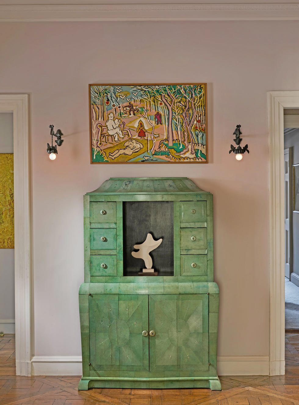 Green cabinet with abstract sculpture and colorful artwork above it.
