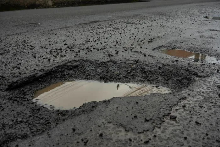 Pothole filled with water on an asphalt road, highlighting urban infrastructure issues