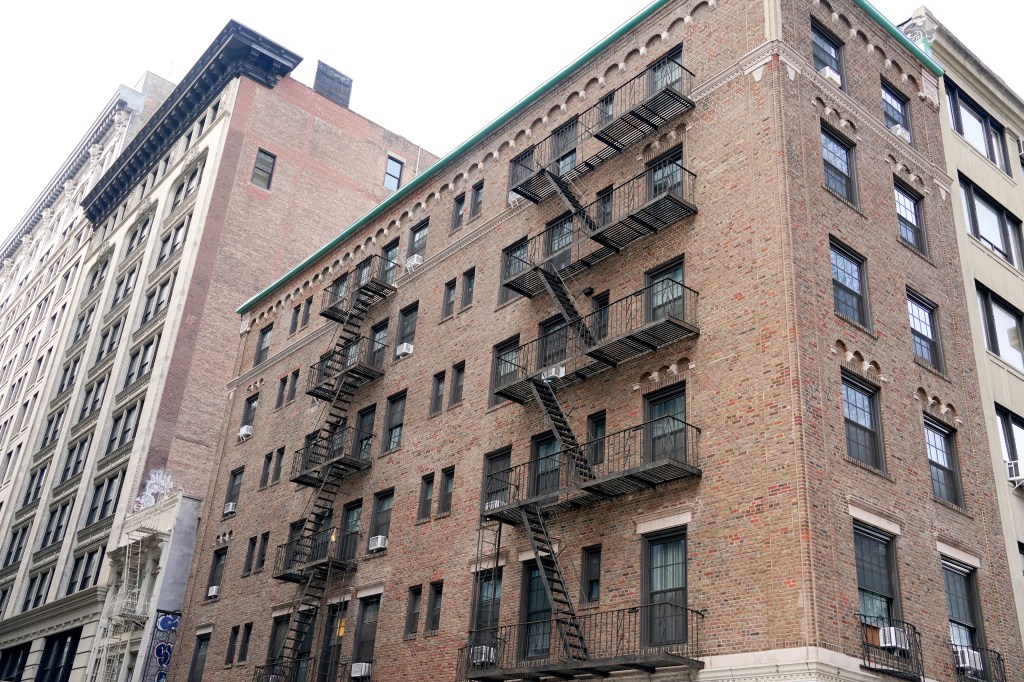 A brick apartment building with several fire escapes zig-zagging up its facade.