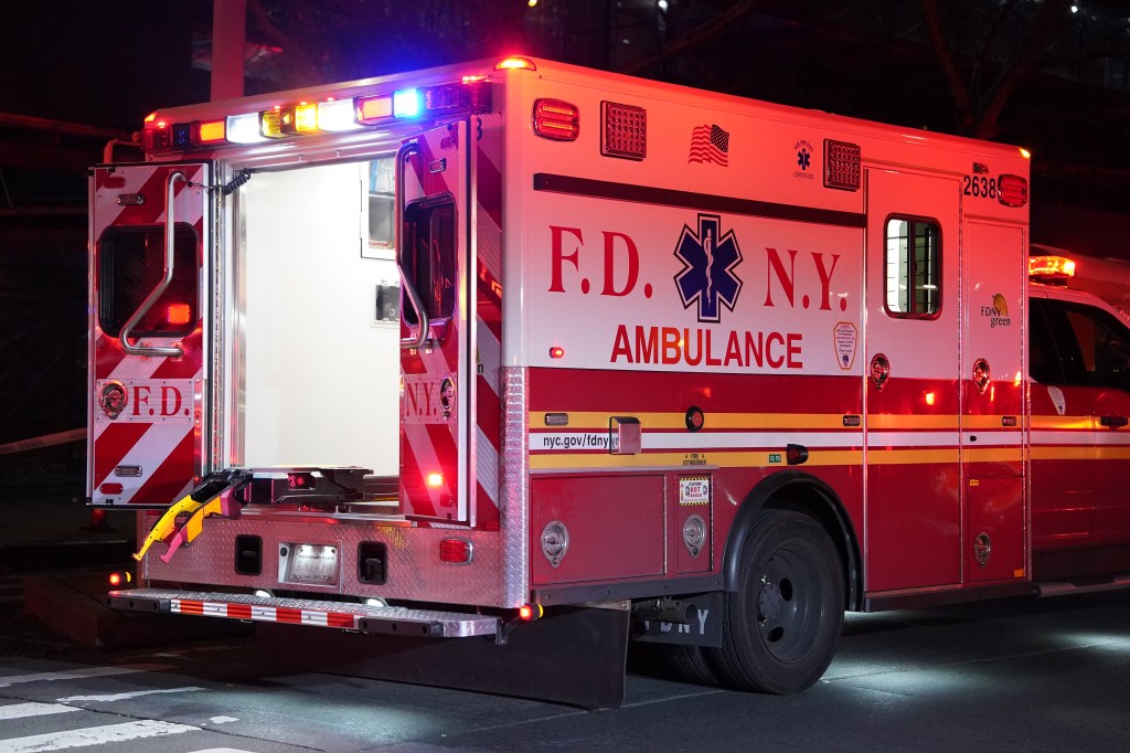 The interior of an FDNY ambulance with flashing lights at a four-alarm fire.