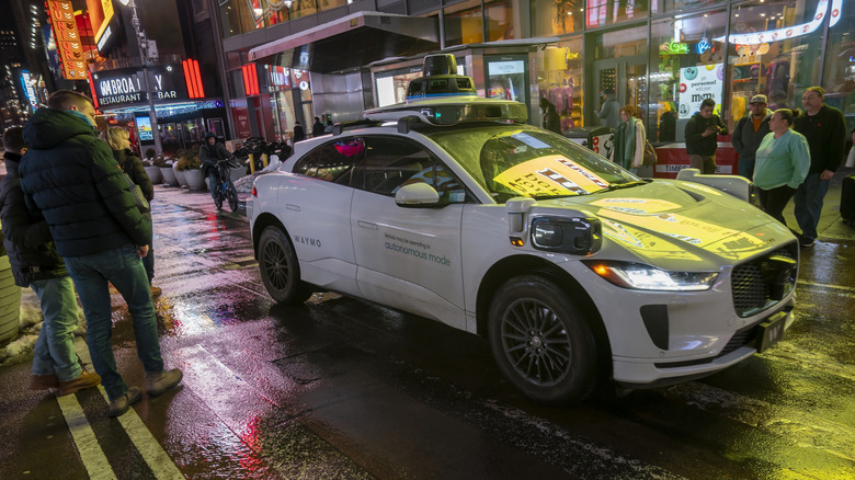 A Waymo robotaxi in New York City's Times Square at night in the rain
