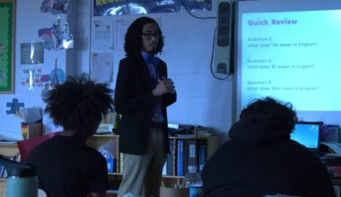 teacher in front of whiteboard with graphic on it during a class
