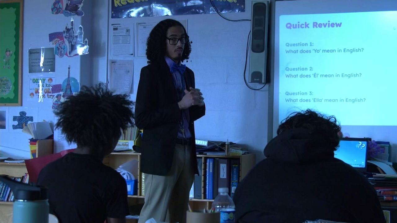 teacher in front of whiteboard with graphic on it during a class