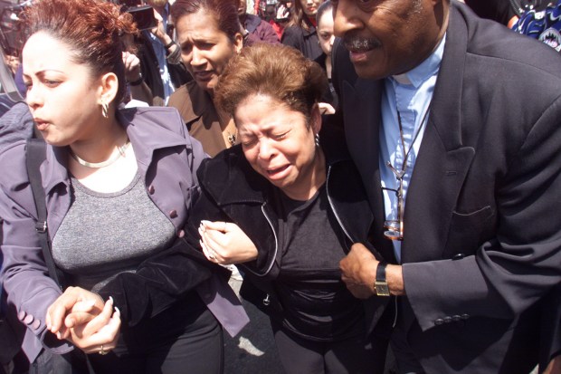 The Rev. Herbert Daughtry assists Divina Lopez (c), the sister livery cab driver Cesar Manuel Lopez, outside St. Malagia Church in Brooklyn, where Lopez's funeral was held on May 2, 2000. (Mike Albans / New York Daily News)