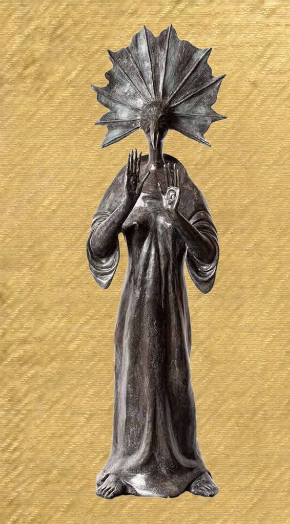 A dark bronze sculpture by Leonora Carrington of a standing, robed figure with a fan-shaped, shell-like head that obscures the face. The figure raises both hands in front of its chest, palms outward, as if gesturing or reading. The long garment drapes to the feet, and the figure stands against a flat, gold-toned background.