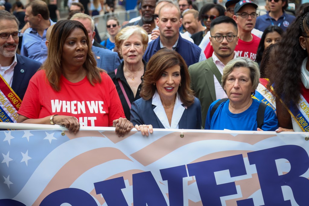 Letitia James, Kathy Hochul, and Randi Weingarten holding a banner at the NYC Labor Day Parade.