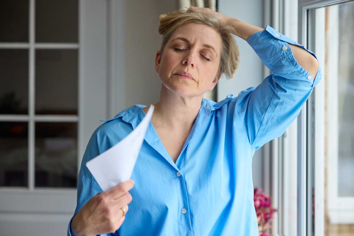 woman in menopause waving paper after having hot flash