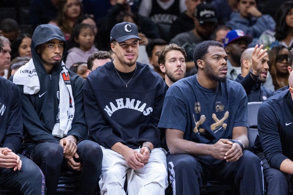 Brooklyn Nets center Nic Claxton, Michael Porter Jr. and Day'Ron Sharpe watching a game from the bench.