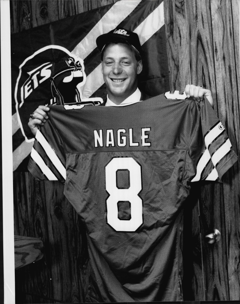 Browning Nagle holding a "NAGLE 8" jersey at a press conference.