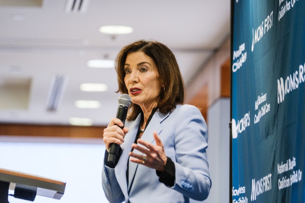 New York Governor Kathy Hochul speaks about childcare costs, holding a microphone.