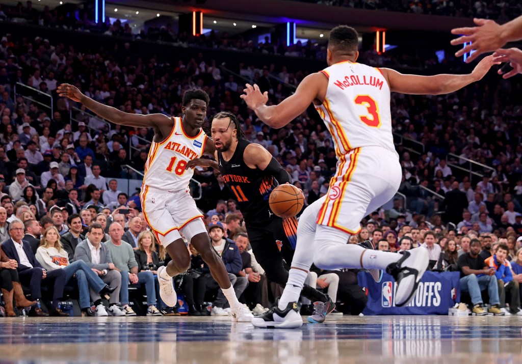 New York Knicks guard Jalen Brunson #11 drives to the basket between Atlanta Hawks forward Mouhamed Gueye #18 and Atlanta Hawks guard CJ McCollum #3.