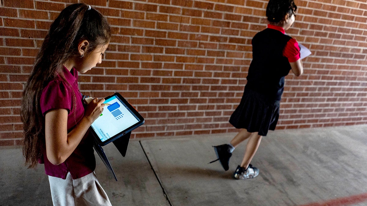 A student uses a tablet as she walks.
