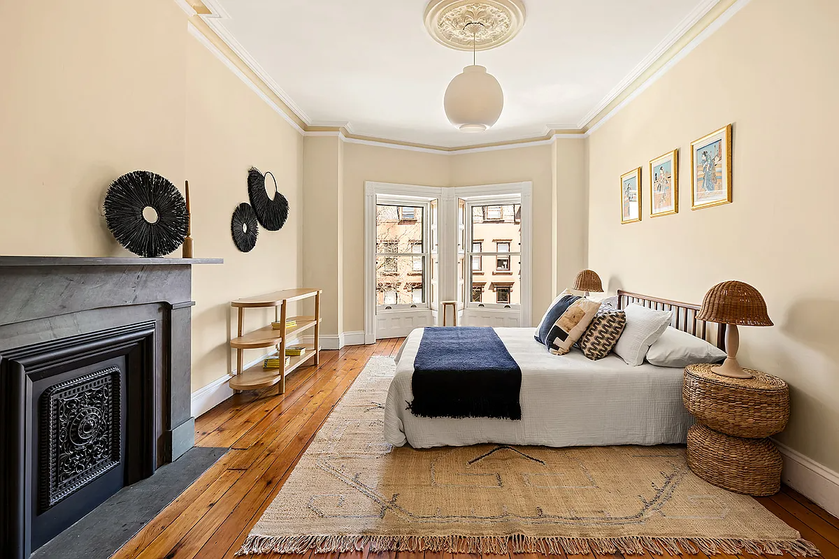 bedroom with wood floor, stone mantel