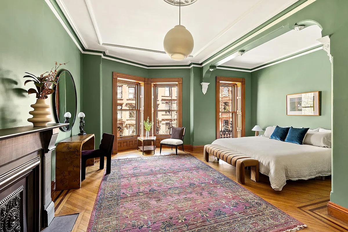bedroom with bed niche, mantel, wood floor