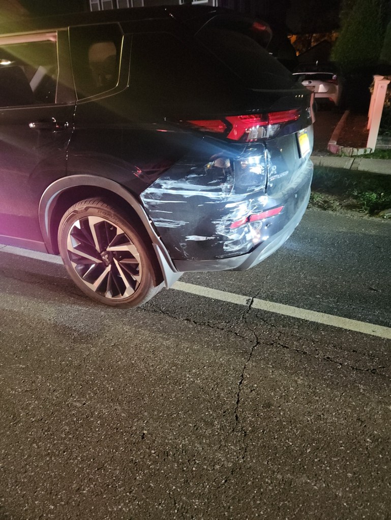 Uber driver's car with significant damage and scratches on its rear bumper.