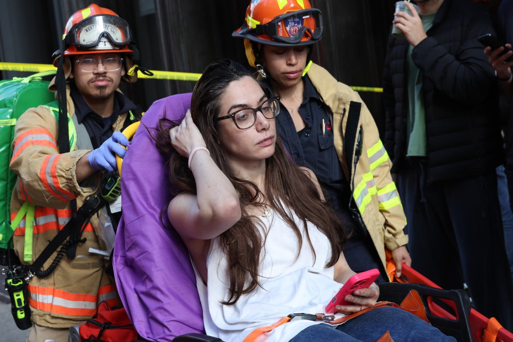 Balic is seen on a stretcher holding her phone. 