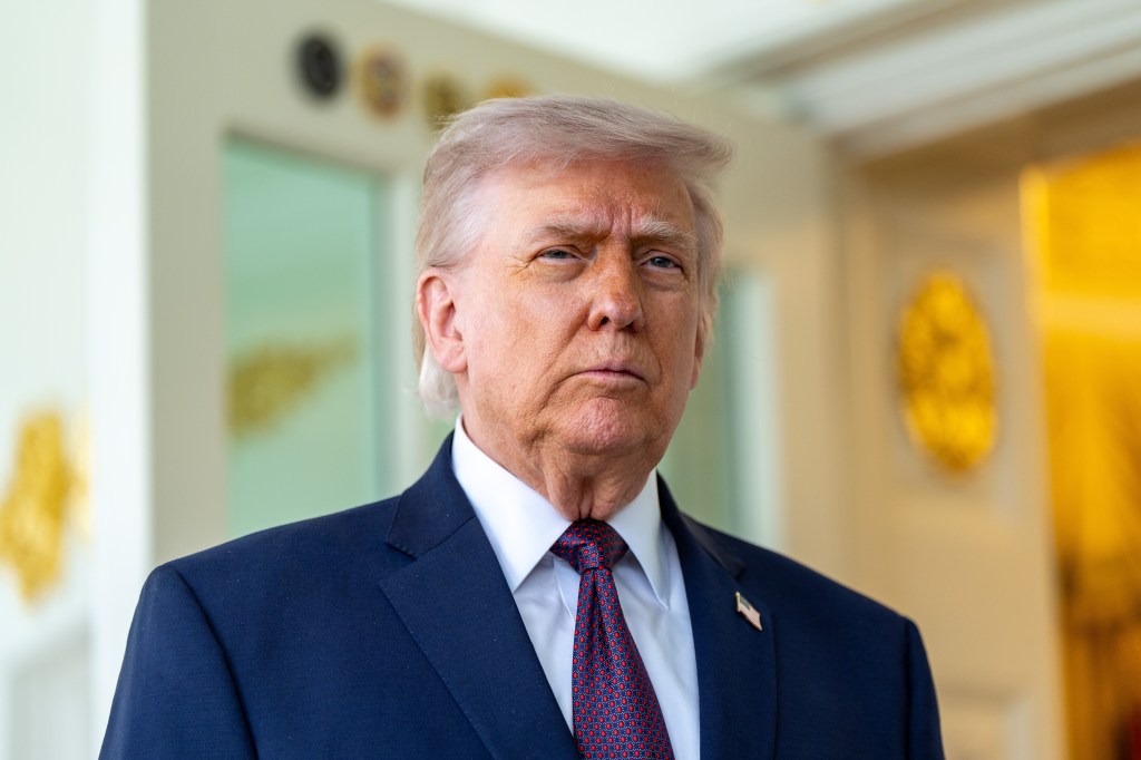President Donald Trump wearing a navy suit, white shirt, and red patterned tie, looking forward.