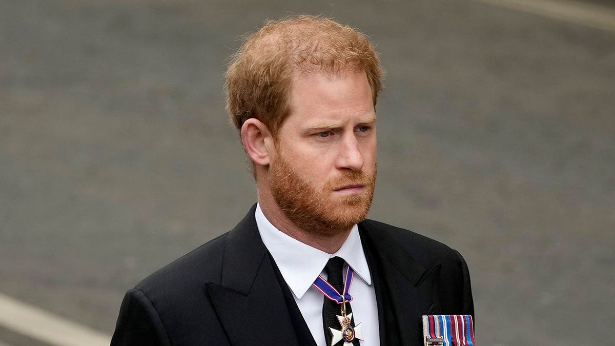 Prince Harry walking at Westminster Abbey in a dark suit