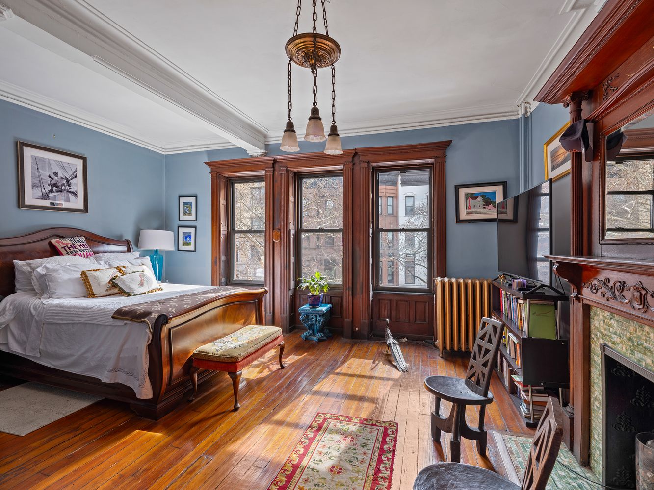 bedroom with a bed nook, wood mantel with original stile surround and a vintage chandelier