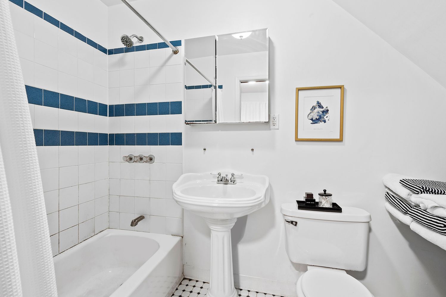 garden level bathroom with white fixtures, white tile on the walls with blue accent tiles
