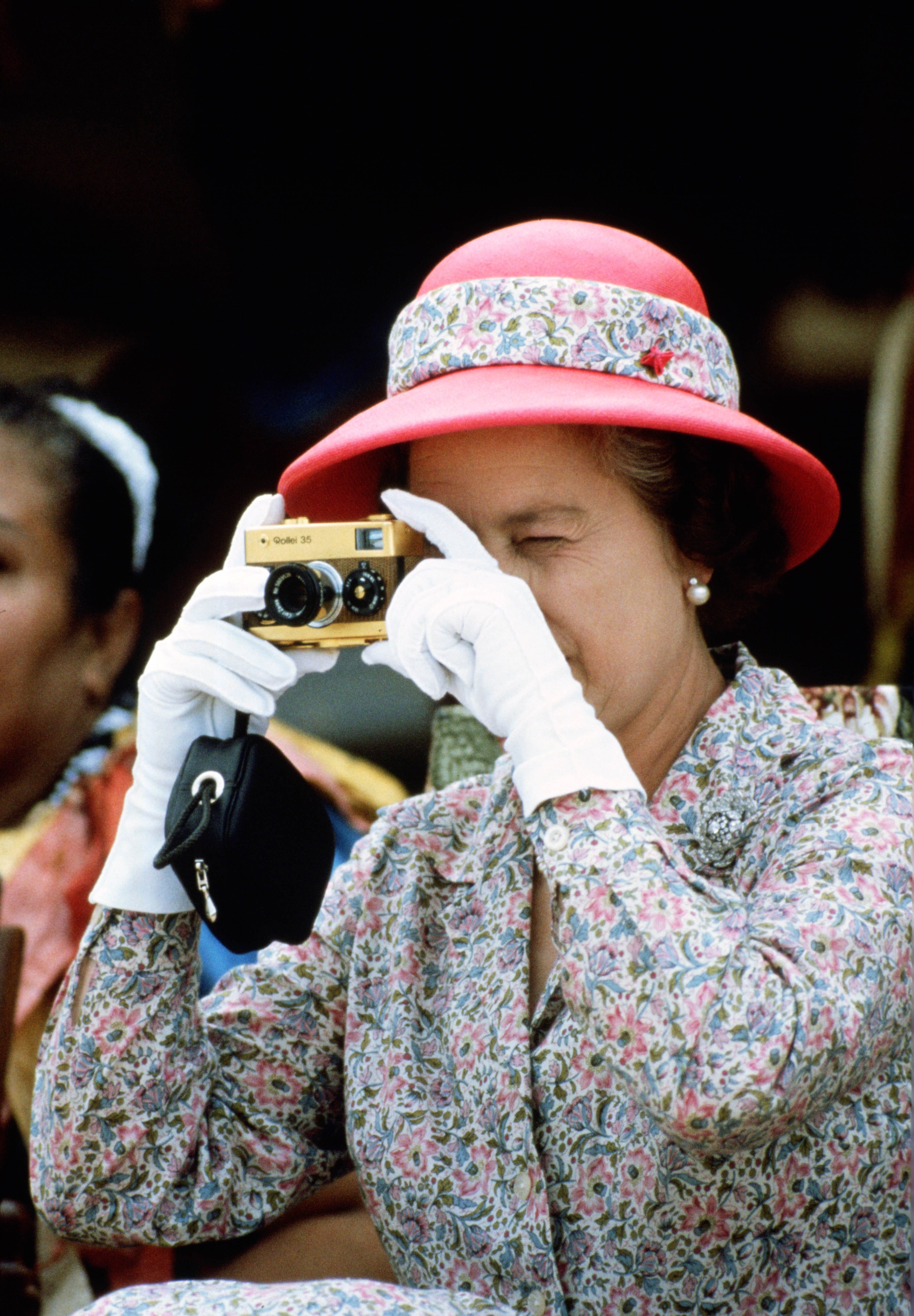 Queen Elizabeth II takes a picture with her camera whilst vi