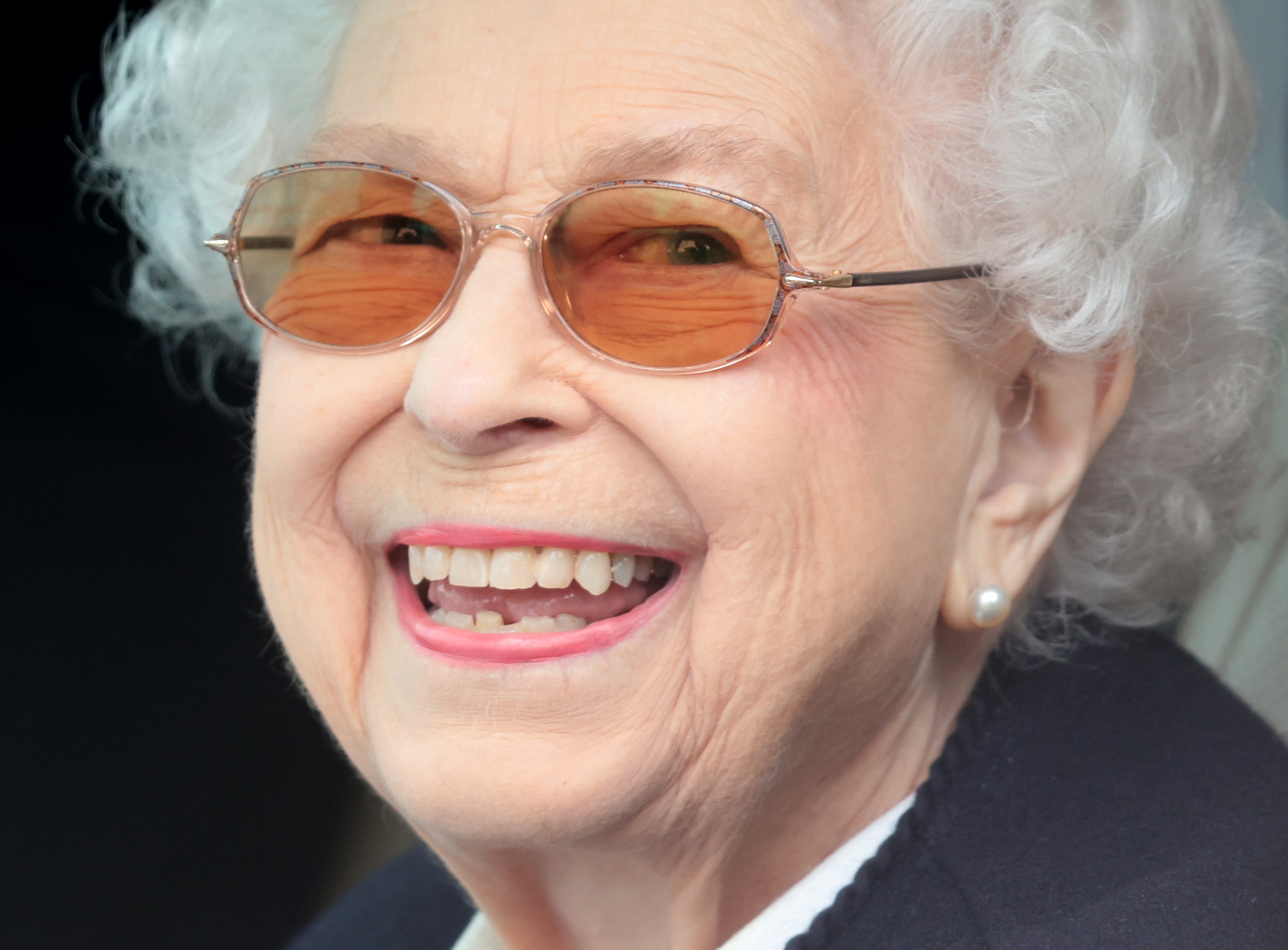 Queen Elizabeth smiling and wearing glasses