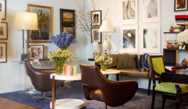 Modern living room with art on walls, brown chairs, floral arrangements on tables, and mixed decor elements.
