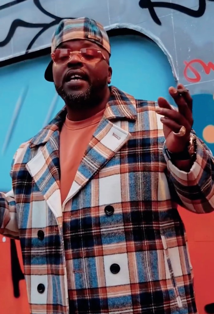 Rapper Jamel Davis (Sinthoro Upper) in a plaid coat and cap.