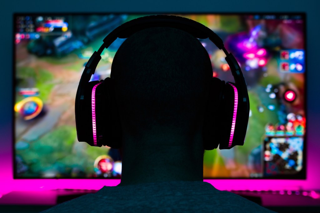 A person with headphones on watching a colorful video game on a screen.