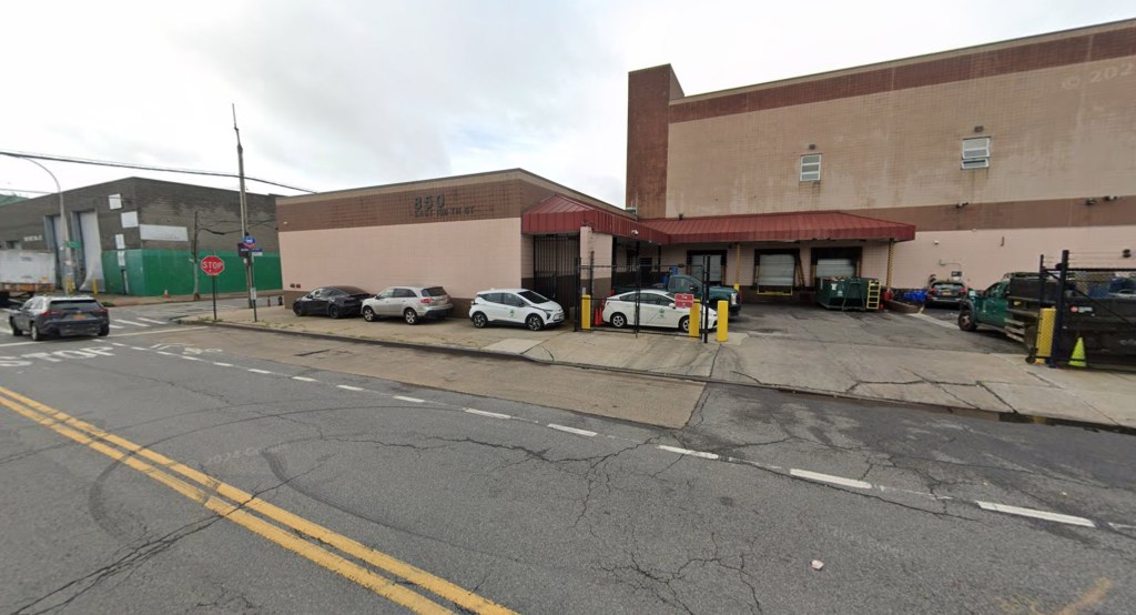 Streetview of 850 East 138th Street in Bronx, NY, showing a light brown and dark brown building with "850 E 138TH ST" written on the facade, with several cars parked on the street.