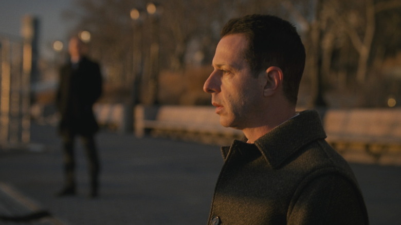 Kendall sitting on a bench being watched in Succession