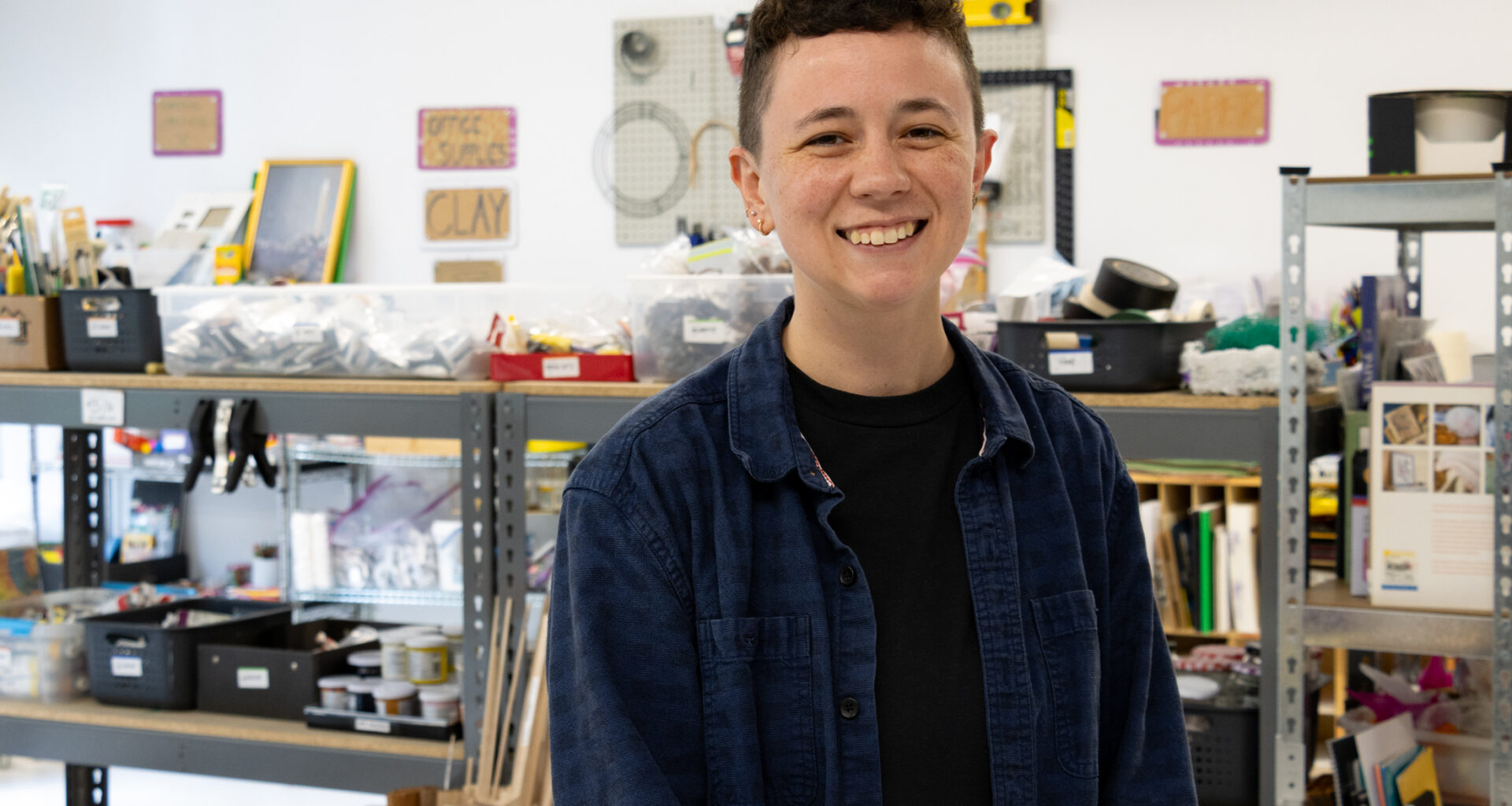 person posing in front of shelves with art and craft supplies