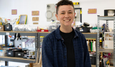 person posing in front of shelves with art and craft supplies