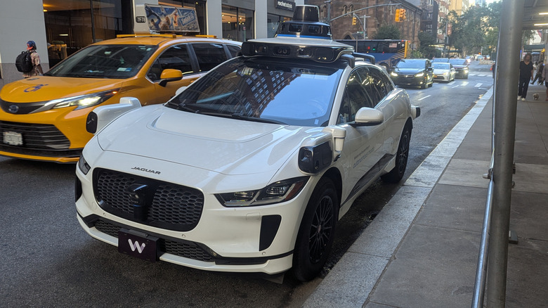Front 3/4 view of a Waymo robotaxi in New York City as a taxi passes by