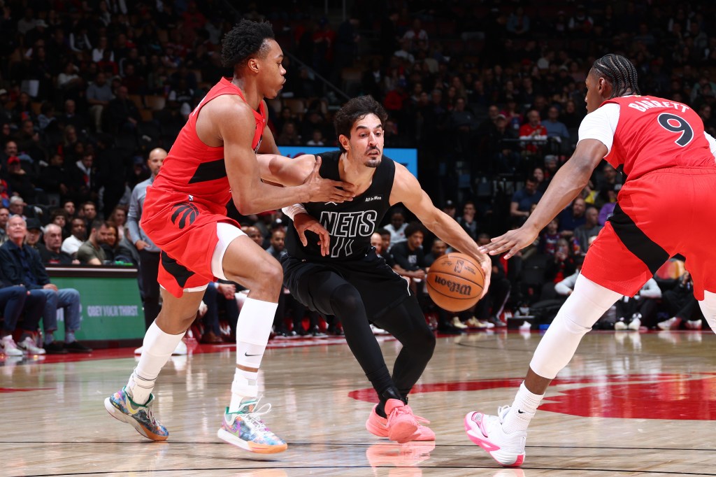 Brooklyn Nets player Ben Saraf handles the ball while being defended by two Toronto Raptors players.